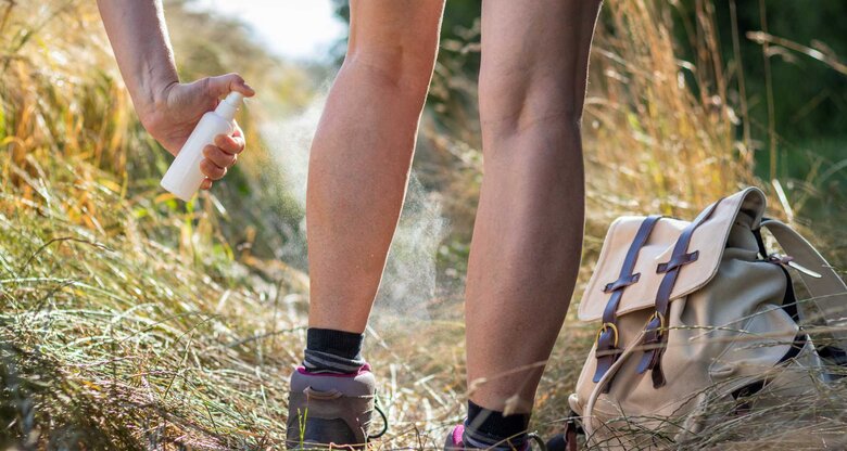 Frau sprüht sich die Beine mit Insektenspray ein | © Adobe Stock/encierro