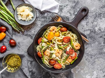 Ein Teller mit Spaghetti, grünem Spargel, Garnelen und frischen Kirschtomaten. | © Getty Images / Westend61