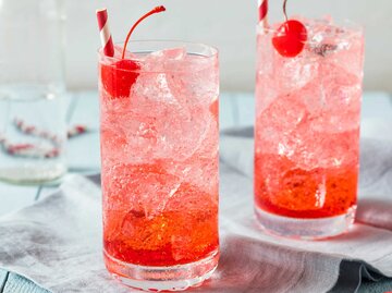 Shirley Temple Mocktail in einem hohen Cocktailglas mit Eis und einer Kirsche als Dekoration | © Getty Images/bhofack2