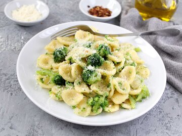 Teller mit Brokkolipasta steht auf dem Tisch und eine Gabel liegt daneben. | © Getty Images / Ale02