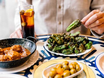 Mann isst gebratene grüne Paprikaschoten (Pimientos de Padrón) mit Wermut in einer Tapas-Bar | © Getty Images/Alexander Spatari