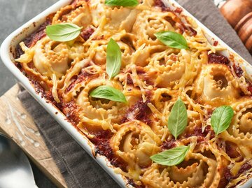  Hausgemachter Lasagne-Pasta-Rotolo-Auflauf mit Tomatensauce, Frischkäse und Basilikum auf weißer Pfanne auf dunklem Schiefer-, Stein- oder Betonhintergrund. Italienisches Küchenkonzept. Draufsicht  | © Getty Images/kasia2003