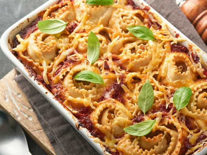  Hausgemachter Lasagne-Pasta-Rotolo-Auflauf mit Tomatensauce, Frischkäse und Basilikum auf weißer Pfanne auf dunklem Schiefer-, Stein- oder Betonhintergrund. Italienisches Küchenkonzept. Draufsicht  | © Getty Images/kasia2003