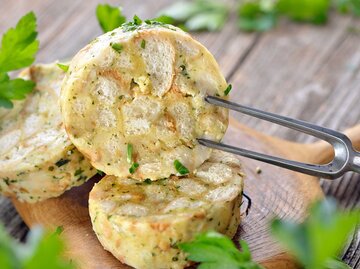 Aufgeschnittene Semmelknödel mit Petersilie liegen auf einem Teller. | © Getty Images / kabVisio