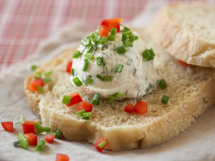 Eine Scheibe Brot mit einem Bällchen Frischkäse | © Getty Images/Westend61