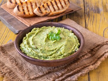 Schüssel mit Bärlauch-Hummus und gegrilltem Brot im Hintergrund | © Getty Images/Costi Moculescu/500px