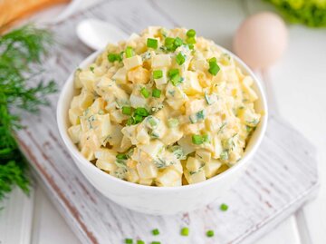 Eiersalat mit gehackten Frühlingszwiebeln oben in einer weißen Schüssel zum Kochen eines Sandwiches auf weißem Holzhintergrund.  | © Getty Images/Irina Taskova