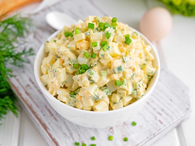 Eiersalat mit gehackten Frühlingszwiebeln oben in einer weißen Schüssel zum Kochen eines Sandwiches auf weißem Holzhintergrund.  | © Getty Images/Irina Taskova