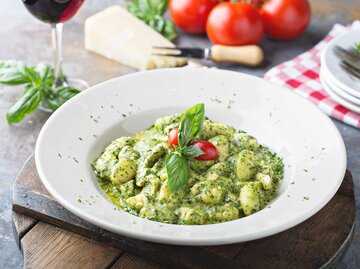 Teller mit leckerem Gnocchi-Pesto-Gericht steht auf einem gedeckten Tisch. | © Adobe Stock/fahrwasser