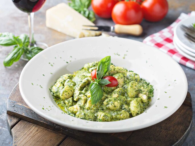 Teller mit leckerem Gnocchi-Pesto-Gericht steht auf einem gedeckten Tisch. | © Adobe Stock/fahrwasser