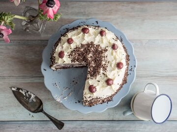 Falsche Schwarzwälder Kirschtorte angeschnitten und auf blauer Kuchenplatter serviert | © Getty Images/Westend61