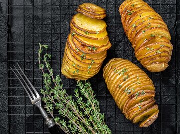 Fächerkartoffeln oder Hasselback-Kartoffeln mit Rosmarin auf einem Gitter | © Getty Images/Vladimir Mironov