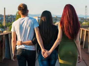 Mann hält hinter dem Rücken seiner Freundin die Hand einer anderen Frau. | © Getty Images/roshinio