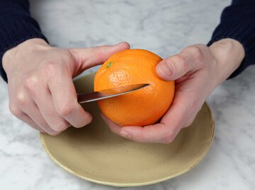 Mann schält eine Orange, Orange Peel Theory | © Getty Images/lma is
