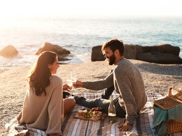 Pärchen macht einen Picknick am Strand | © Getty Images/PeopleImages
