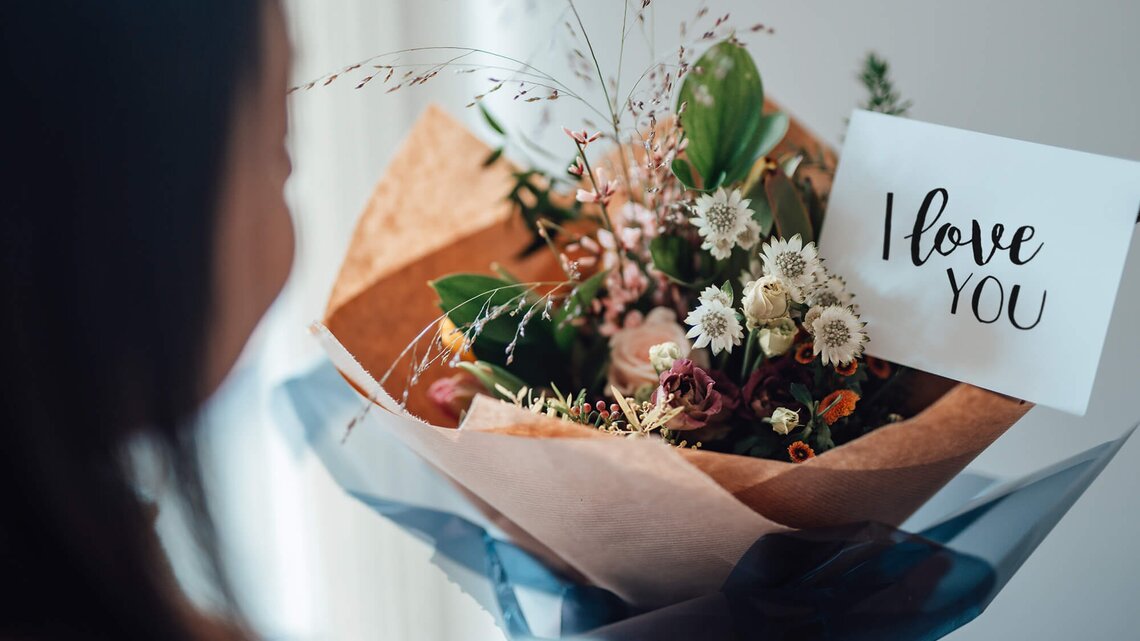 Frau erhält Blumenstrauß mit Karte "I love yu" | © Getty Images/Oscar Wong
