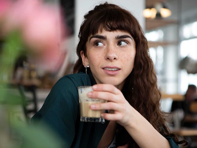 Junge Frau mit Kaffee in der Hand und skeptischem Blick | © Getty Images/Westend61