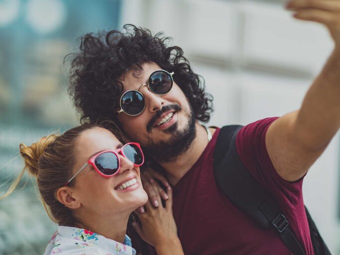 Junges Pärchen mit Sonnenbrille macht ein Selfie von sich | © Getty Images/Jasmina007