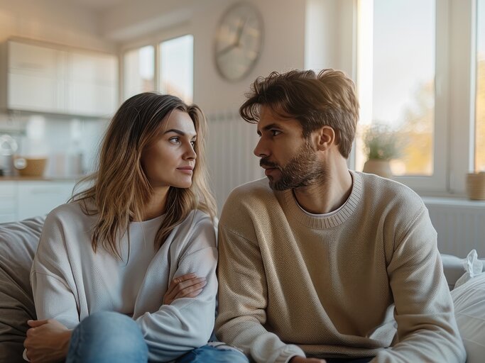 Frau und Mann sitzen auf dem Sofa und schauen sich an | © AdobeStock/Milos