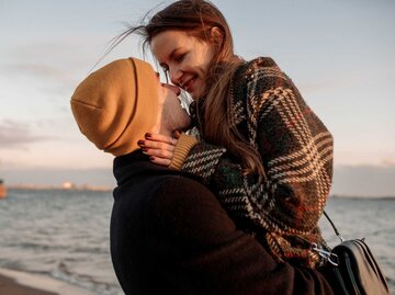 Junges schönes Paar auf einem Spaziergang am Meer im Herbst in der Nebensaison, umarmen, gehen, lächelnd | © Adobe Stock/Maria