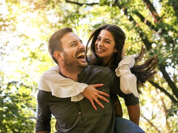 Mann trägt seine Freundin Huckepack. Beide lachen. | © Adobe Stock/liderina