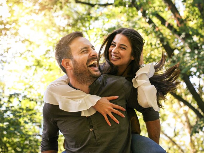 Mann trägt seine Freundin Huckepack. Beide lachen. | © Adobe Stock/liderina