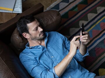 Person mit Handy auf Couch | © Getty Images/Westend61