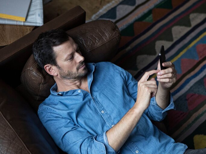 Person mit Handy auf Couch | © Getty Images/Westend61