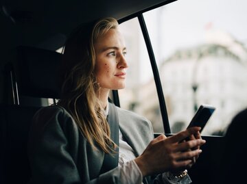 Person in Auto mit Handy | © Getty Images/Maskot