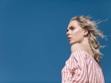 Junge Frau trägt ein gestreiftes Off-Shoulder-Oberteil | © Getty Images/Westend61