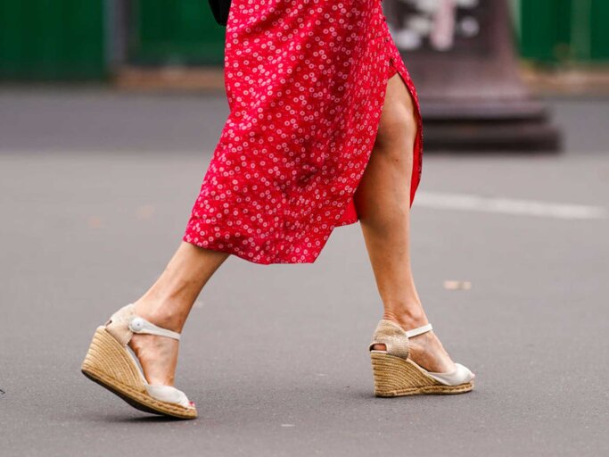 Frau trägt Espadrilles und rotes Sommerkleid | © Getty Images/Edward Berthelot 