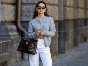 Person in Cardigan, weißer Jeans und Sonnenbrille | © Getty Images/Christian Vierig