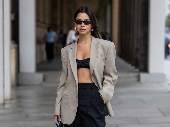 Frau trägt einen Oversized Blazer in Beige und ein schwarzes Bustier | © Getty Images/Christian Vierig 