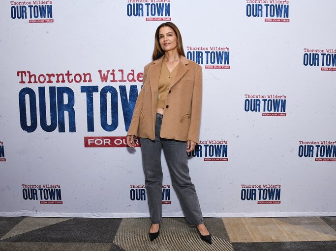 Katie Holmes in Camel-Mantel und -Cardigan, dunkelgrauen Jeans und schwarzen Slingbacks | © Getty Images/Kristina Bumphrey