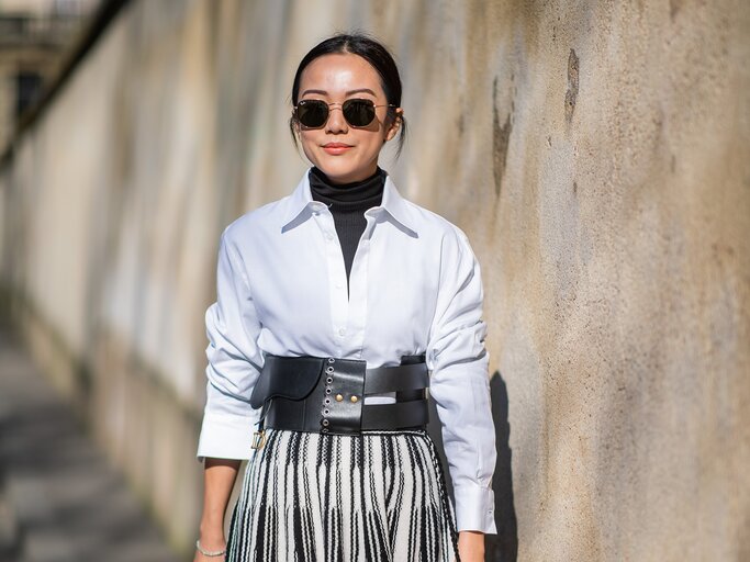 Streetstyle von Frau, die weiße Bluse über schwarzem Rollkragenpullover trägt | © Getty Images/Christian Vierig