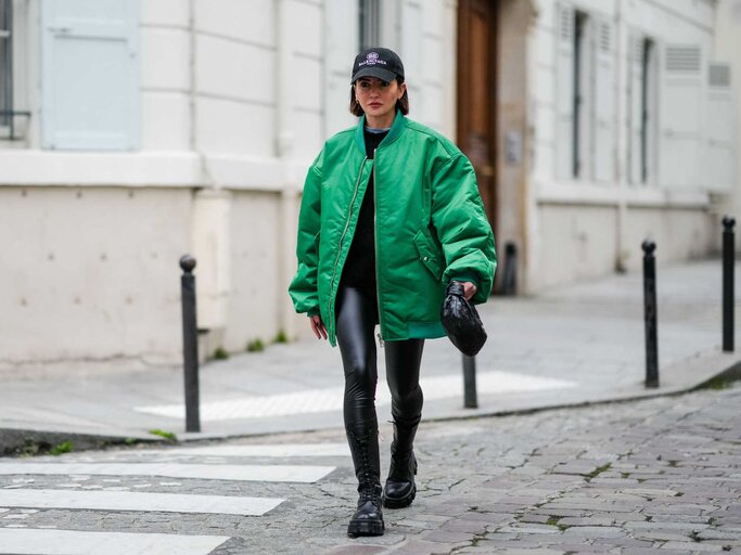 Frau trägt Lederleggings und auffällige grüne Bomberjacke. | © Getty Images/Edward Berthelot