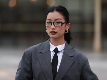 Streetstyle von Thanya Wong in grauem Blazer, weißer Bluse, schwarzer Krawatte und schwarzer Brille | © Getty Images/Jeremy Moeller