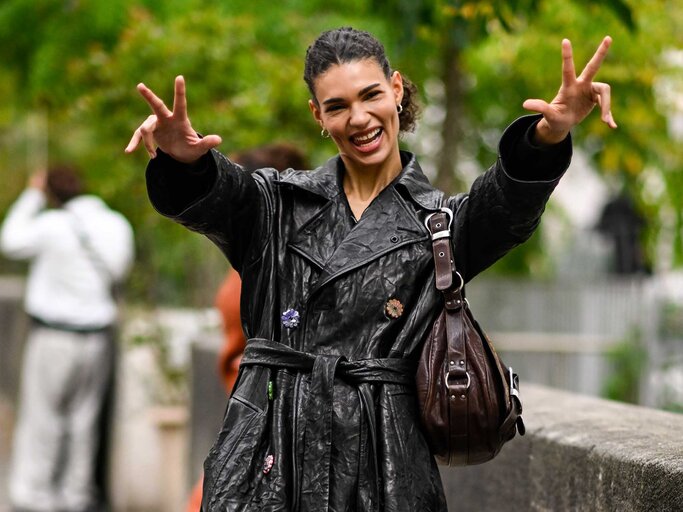 Barbara Valente streckt ihre Hände in die Kamera und trägt einen schwarzen Trenchcoat. | © Getty Images/Daniel Zuchnik