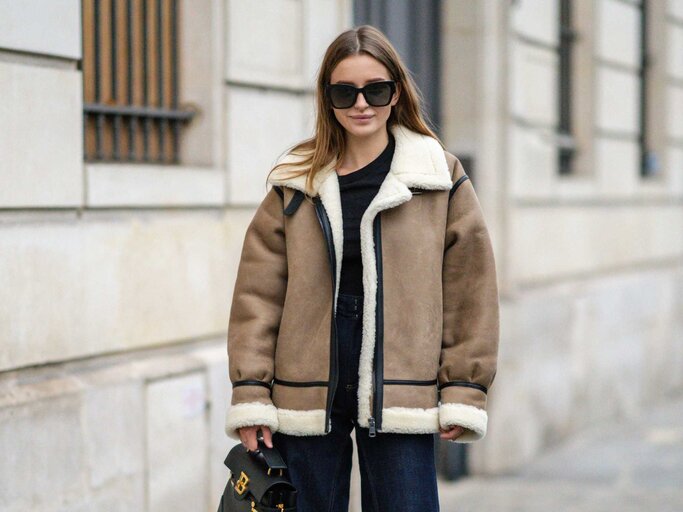 Frau trägt eine dicke Winterjacke und Sonnenbrille | © Getty Images/Edward Berthelot 