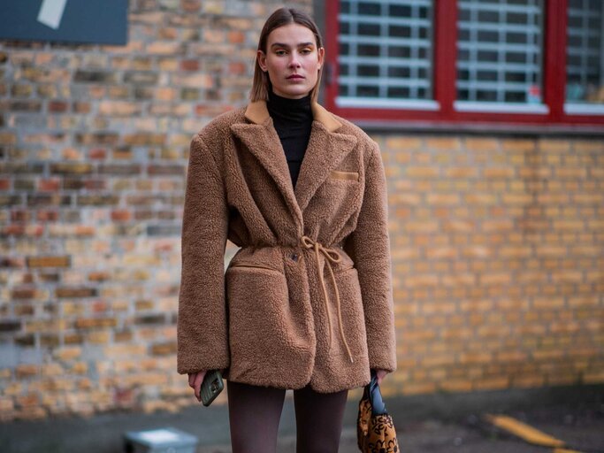 Frau trägt Leggings, Boots und eine weite Jacke | © Getty Images/Christian Vierig