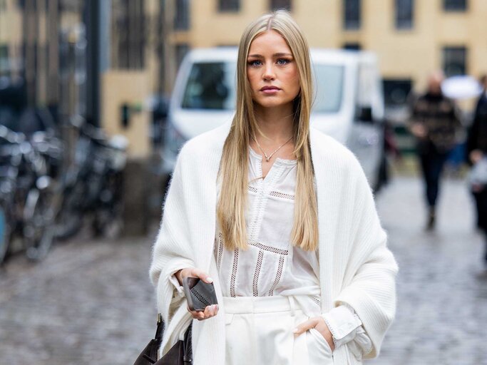 Eine blonde Frau auf der Copenhagen Fashion Week in einem komplett weißen Outfit mit Boho-Bluse. | © Getty Images/Christian Vierig