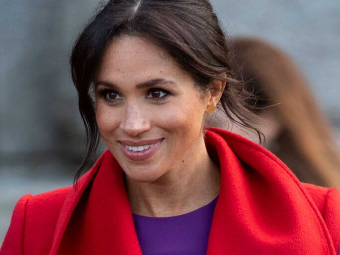 Meghan Markle trägt einen roten Mantel und eine lila Bluse | © Getty Images/Mark Cuthbert 