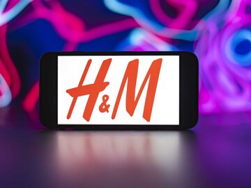 H&M Logo auf einem Handybildschirm vor einem bunten Hintergrund. | © Getty Images/SOPA Images