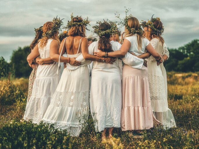 Frauen tanzen in weißen Kleidern und mit Blumenkränzen im Haar | © AdobeStock/jozefklopacka