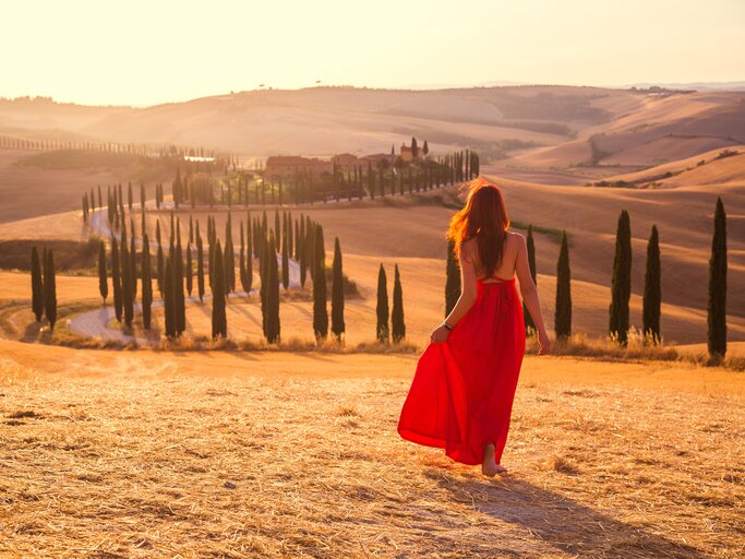 Toskana-Landschaft mit Frau in rotem Kleid im Vordergrund | © AdobeStock/Vladimir Sobko