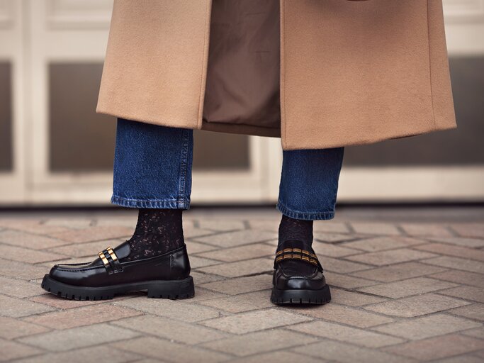 schwarze Loafer, Jeans, Mantelsaum | © Adobe Stock/Anna Zhuk