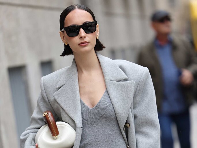 Frau trägt Sonnenbrille und graues Strickkleid | © Getty Images/Claudio Lavenia 