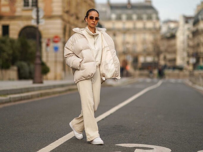 Frau in beigem Outfit mit einer hellen Winterjacke | © Getty Images/Edward Berthelot