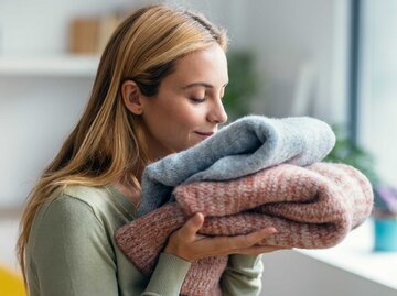 Junge Frau riecht zufrieden an Wäsche. | © Getty Images/nensuria