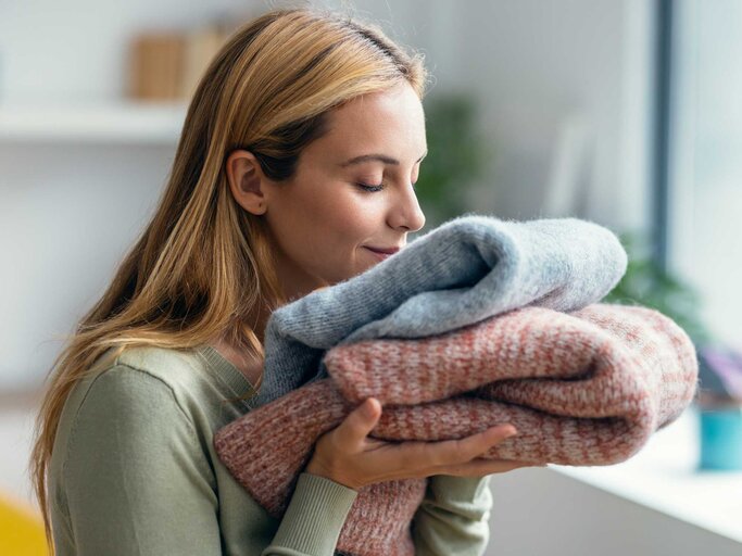 Junge Frau riecht zufrieden an Wäsche. | © Getty Images/nensuria